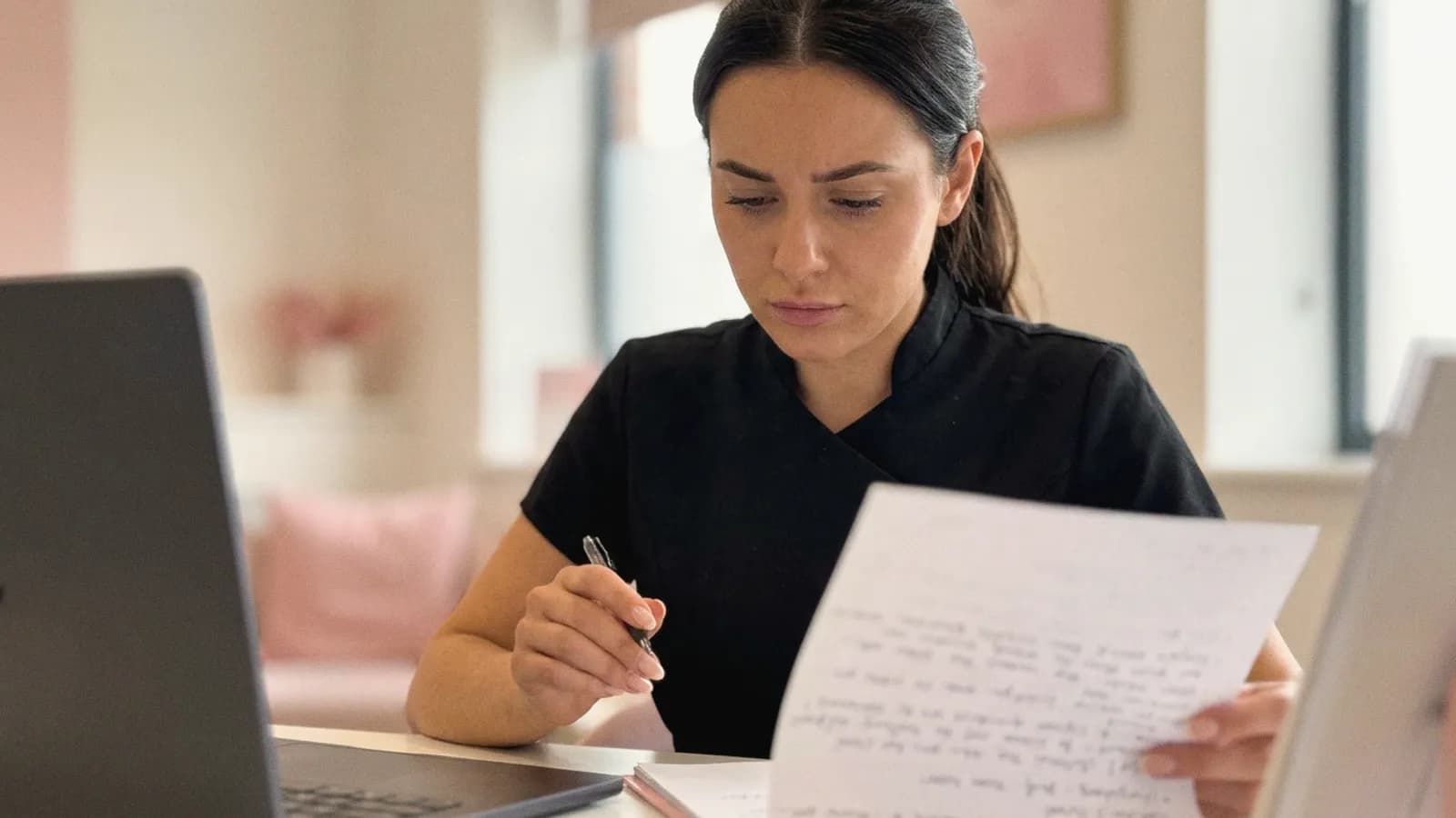 A practitioner rereads her handwritten consultation notes at her desk.